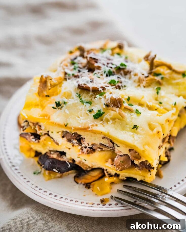 A slice of mushroom lasagna with a fork on a plate.