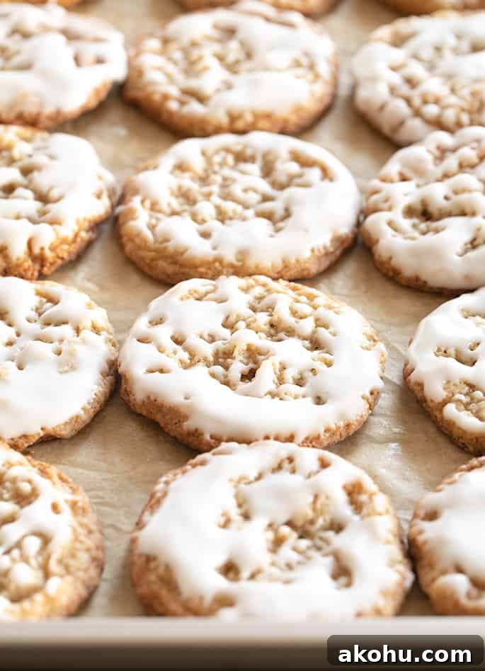 Thin Chewy Gluten-Free Iced Oatmeal Cookies 5 Thin and chewy gluten free oatmeal cookies with light icing on top on a baking tray