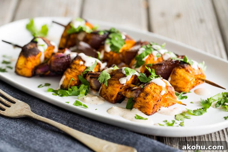 BBQ paprika sweet potato skewers with a lemon tahini sauce make a fantastic vegetarian and vegan BBQ grilled side dish to serve up this summer or can go with meat, fish and cheese really well. Using just sweet potato, and red onion coated in warming paprika, plus a sauce of tahini, lemon juice and gentle cinnamon, topped with coriander, these skewers are sure to make everyone around the lunch or dinner table happy!