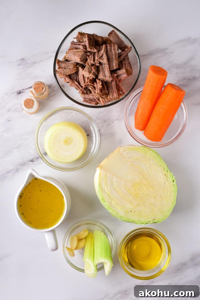 On a marble surface lie the ingredients for a delicious cabbage stew recipe: shredded beef, carrots, onion, cabbage, broth, garlic, celery, olive oil, and spices.