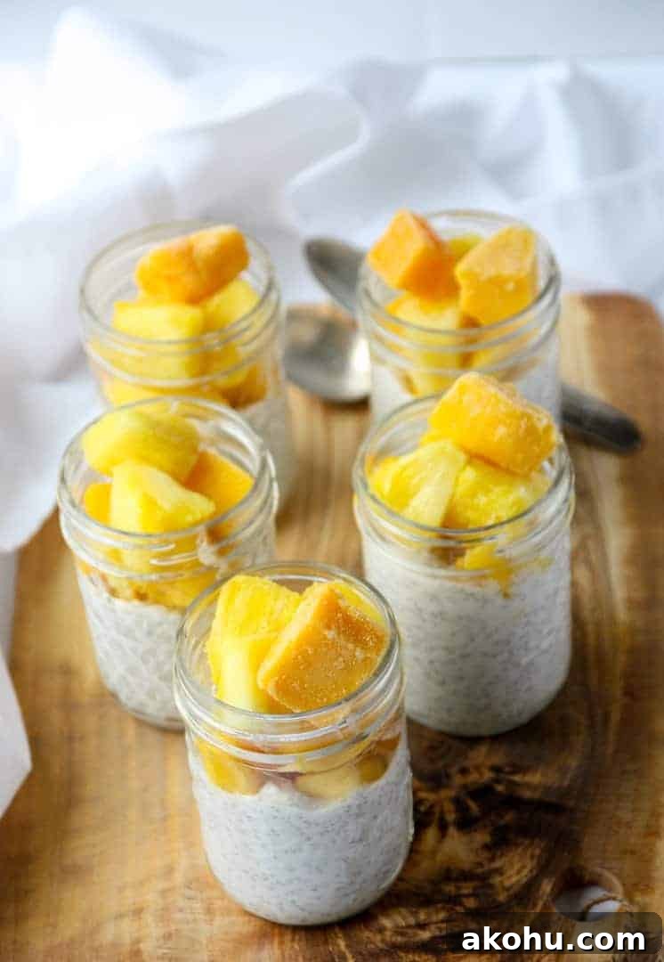 Five half pint jars of coconut chia pudding topped with mango and pineapple.