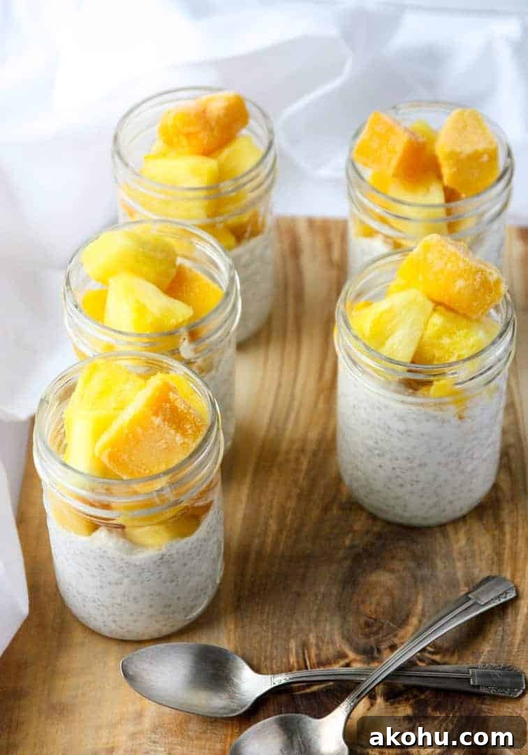 Four glass jars filled with coconut chia pudding and fruit.