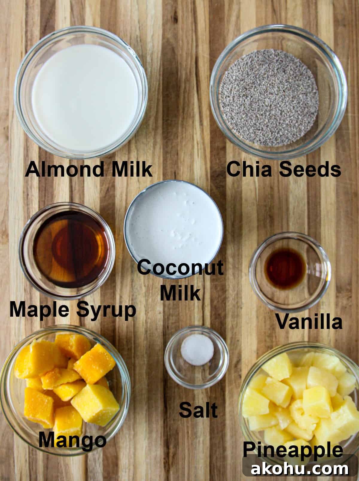 All of the ingredients for coconut milk chia pudding in glass bowls on a wooden board.