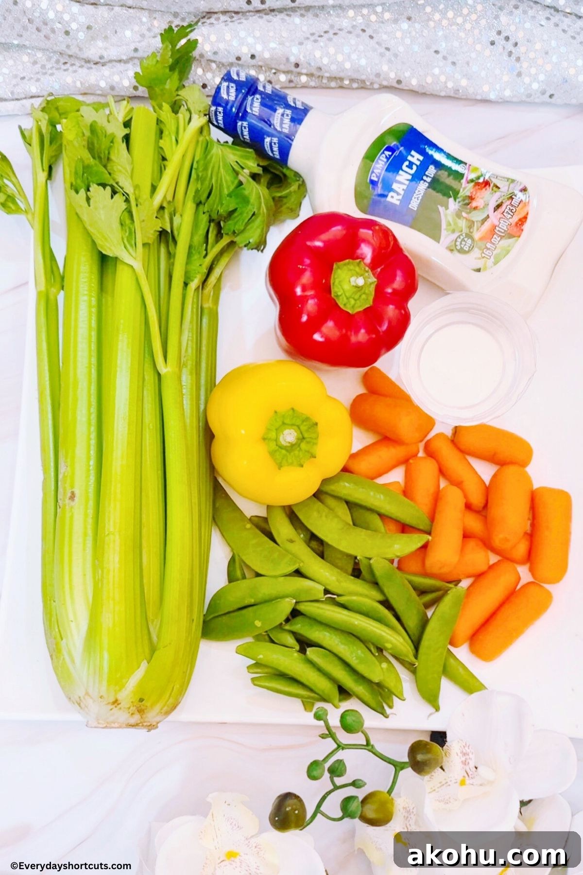 Blooming Vegetable Platter: Stunning Veggie Flower Tray Tutorial 4 celery stalk red bell pepper yellow bell pepper bowls ranch dressing baby carrot and snap peas on a white board