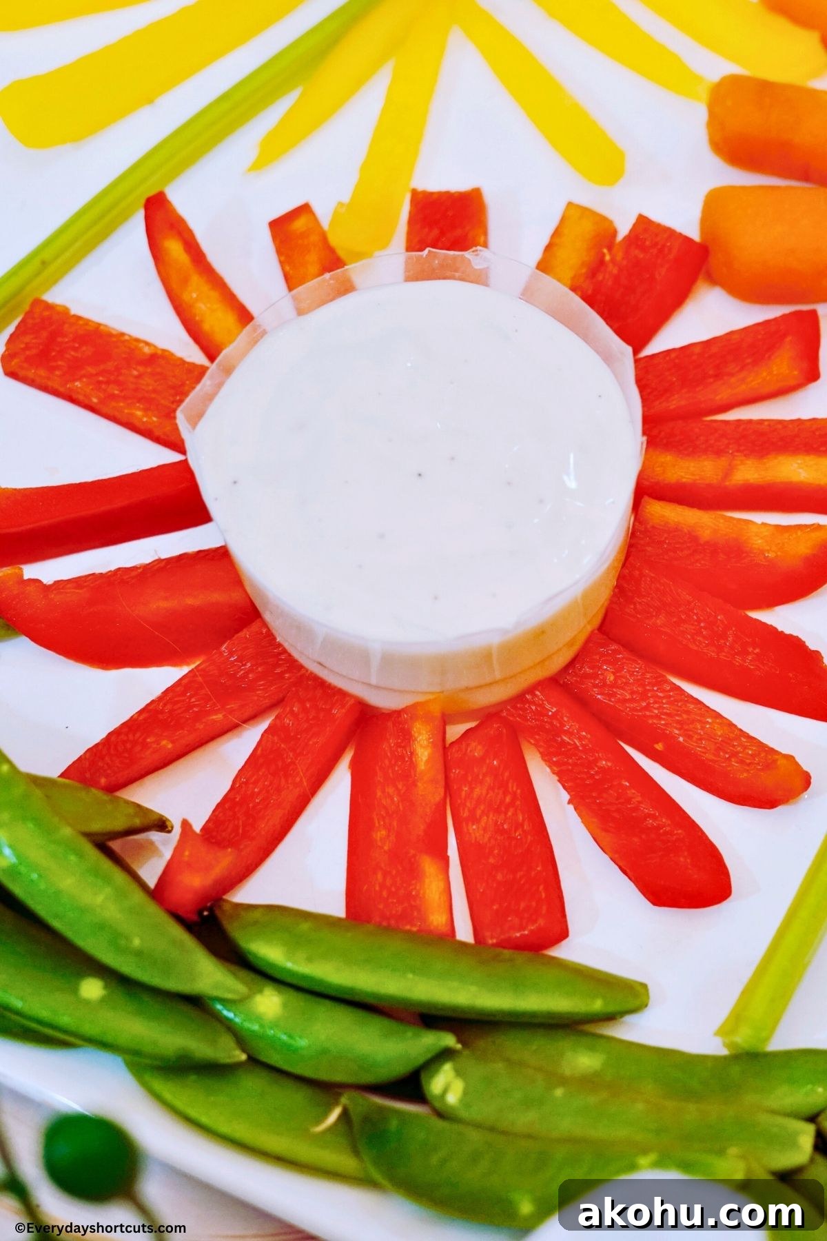 Blooming Vegetable Platter: Stunning Veggie Flower Tray Tutorial 6 red bell pepper strips in a circular pattern with a bowl of ranch dressing in the middle of it
