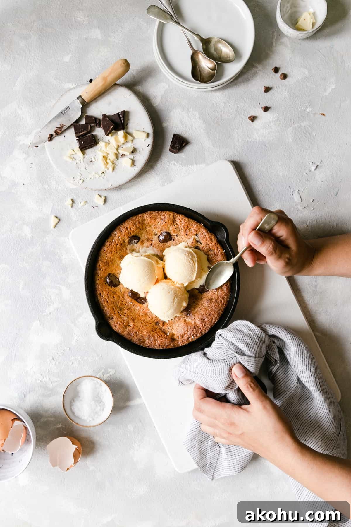 top view of a person holding skillet with chocolate chip cookie topped with vanilla ice cream