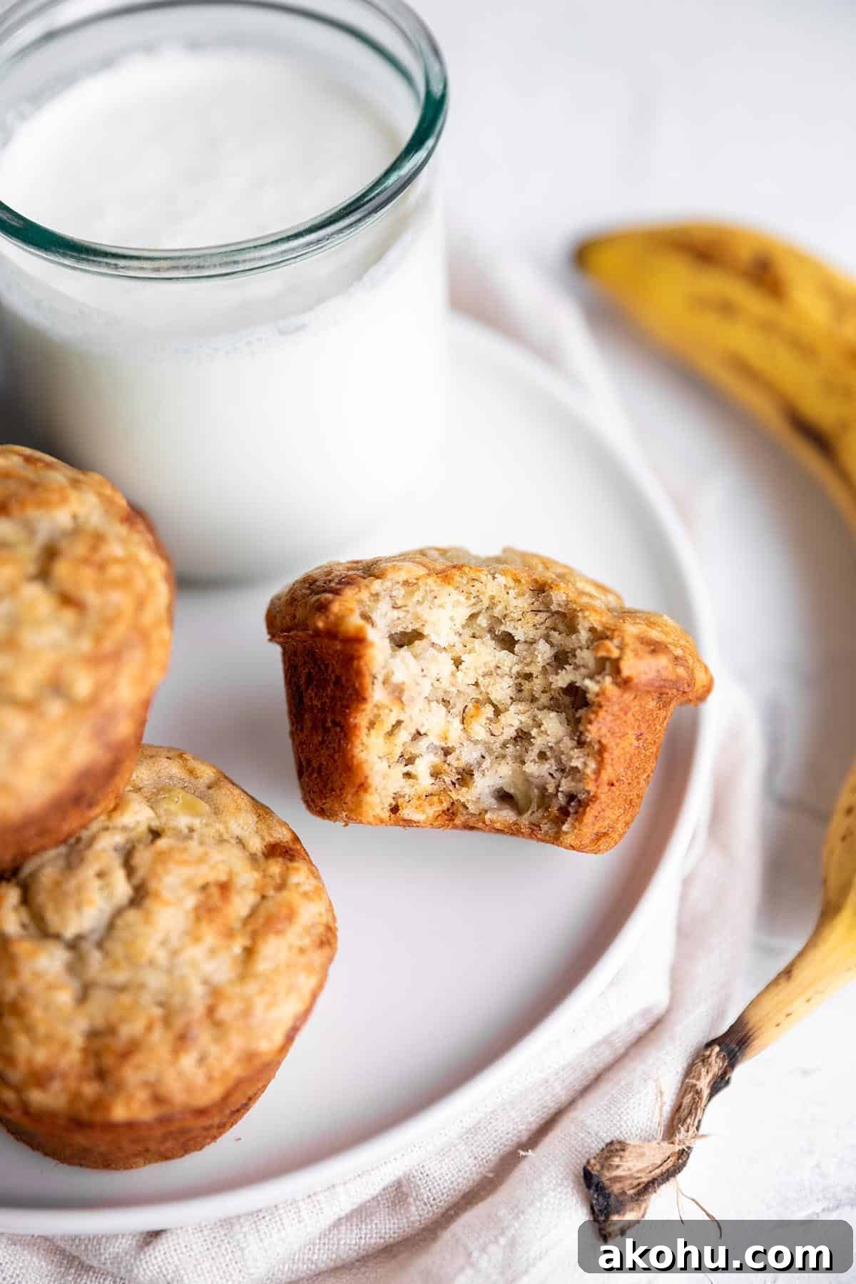 Sourdough Banana Muffins with Cinnamon Streusel 7 A banana muffin on a plate with a glass of milk and banana.