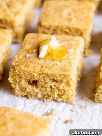 A piece of sourdough cornbread with some butter and honey on top.