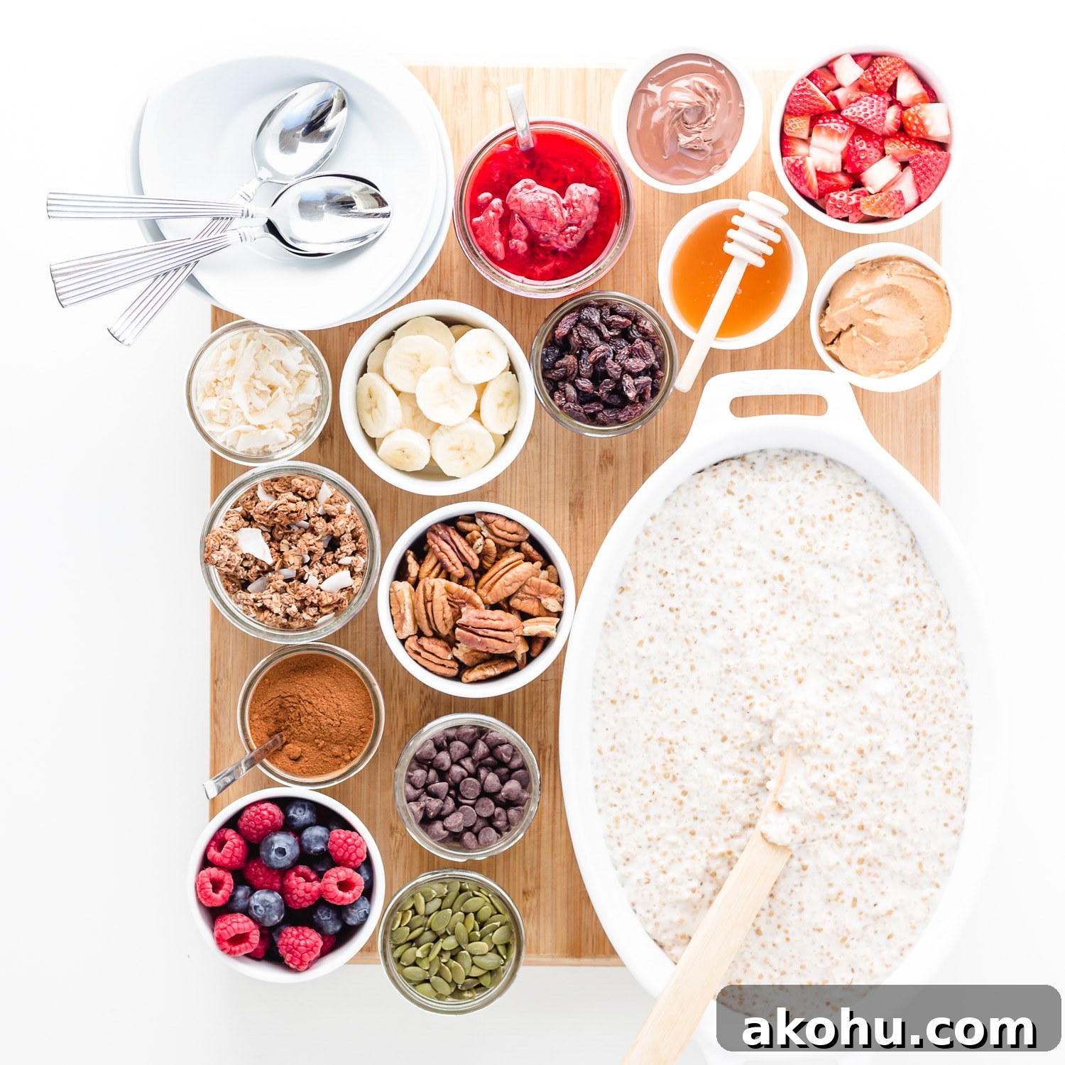 An oatmeal breakfast board featuring a variety of toppings set out in little bowls on a board alongside a big dish of oatmeal.