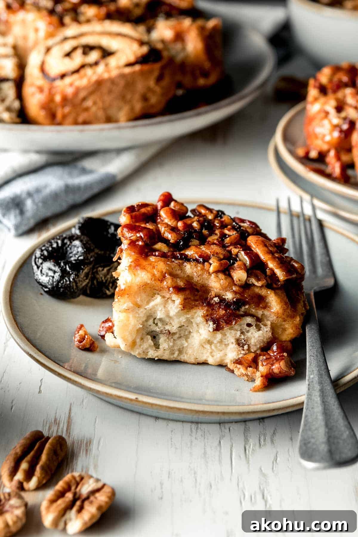 A gluten free sticky roll on a plate showing fluffy texture and shiny pecan caramel topping.