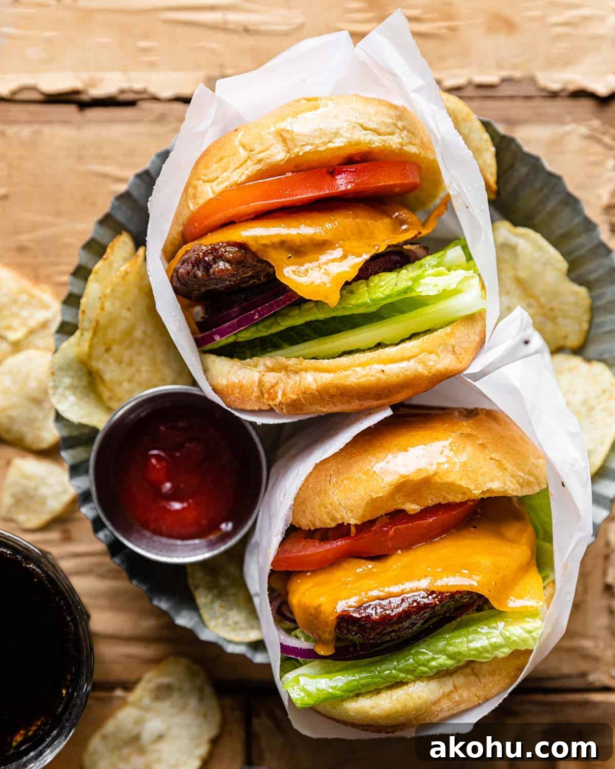 Overhead image of hamburgers with toppings wrapped in parchment paper.