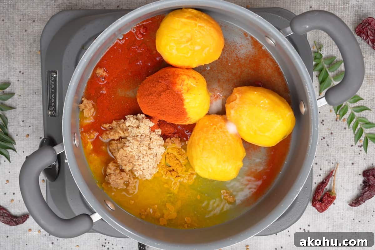 mangoes, jaggery, salt, chili powder, turmeric powder and water added to a pan.