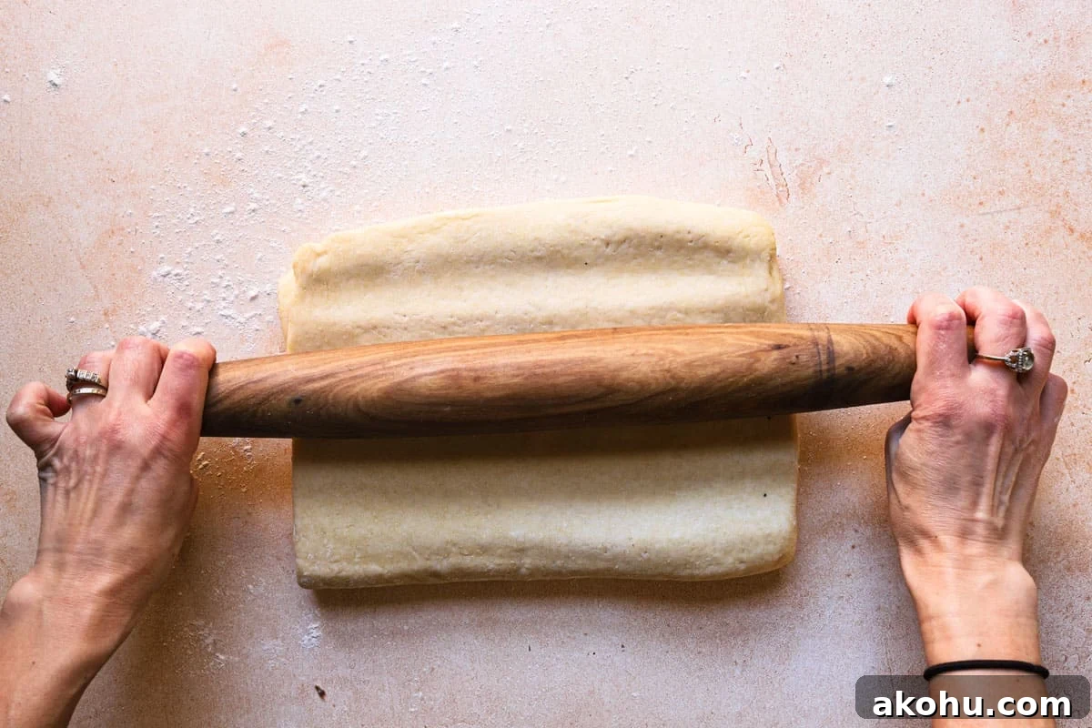 Hands tapping dough with a rolling pin