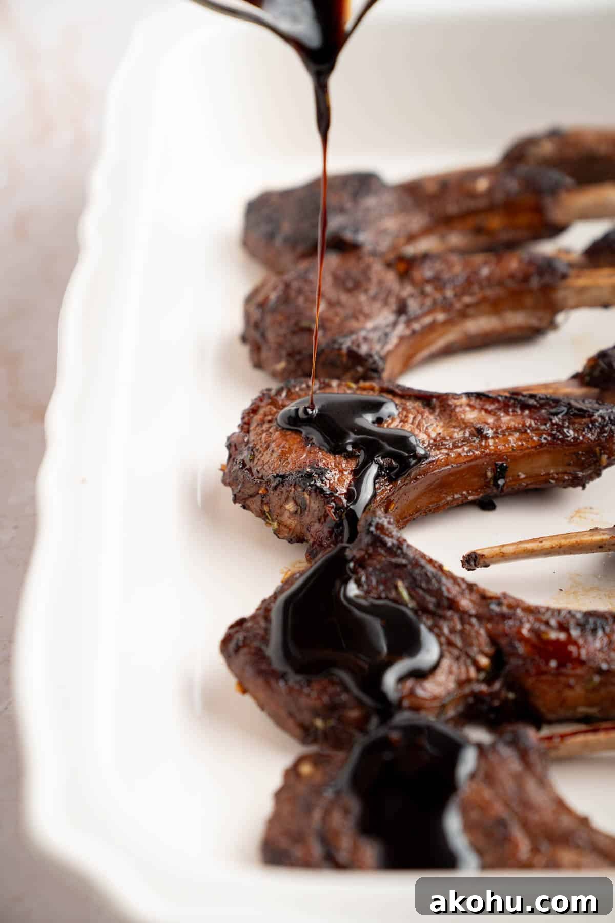 Balsamic-Glazed Oven Roasted Lamb Chops for Dinner 8 A spoon pours the glaze over the lamb chops before broiling in the oven.