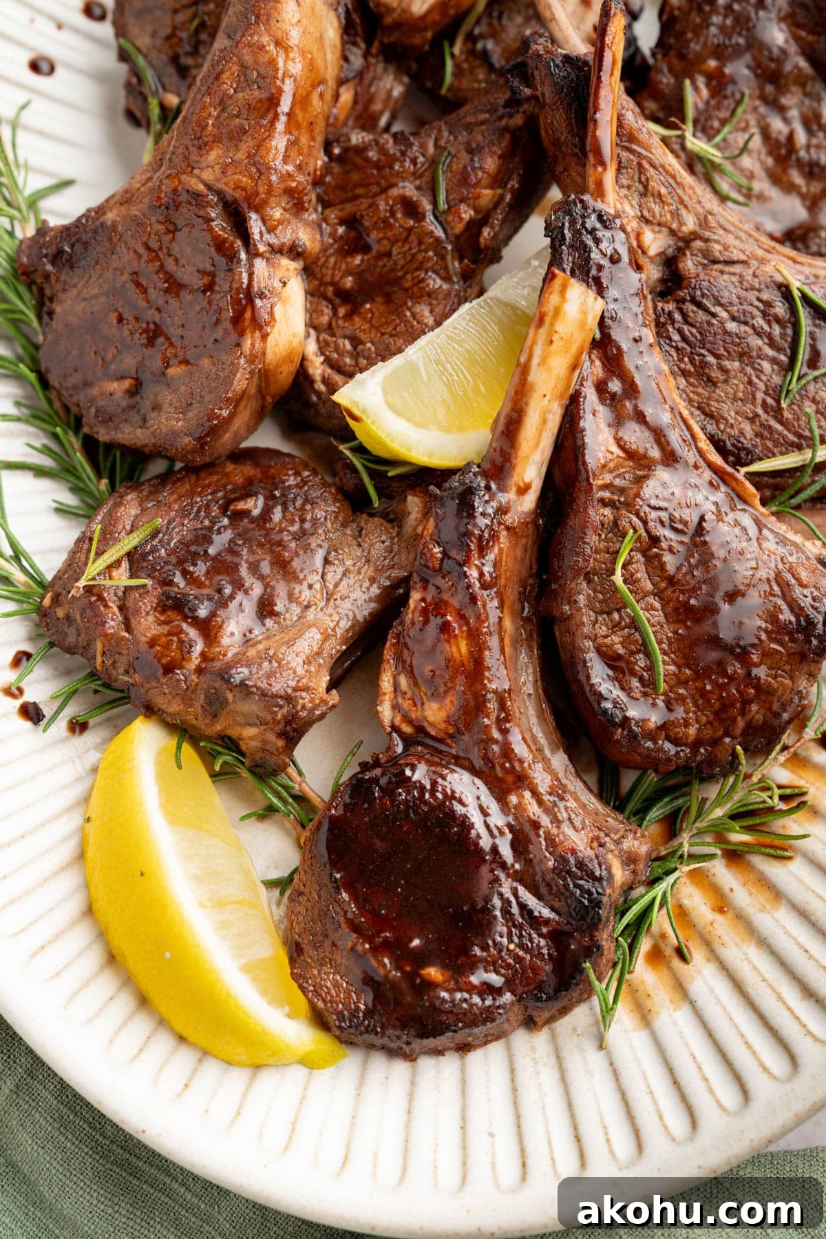 Balsamic-Glazed Oven Roasted Lamb Chops for Dinner 10 Oven baked lamb chops with balsamic glaze on a serving platter garnished with fresh rosemary and lemon wedges.