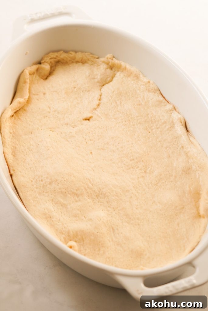 peach filling topped with crescent roll dough in a baking dish