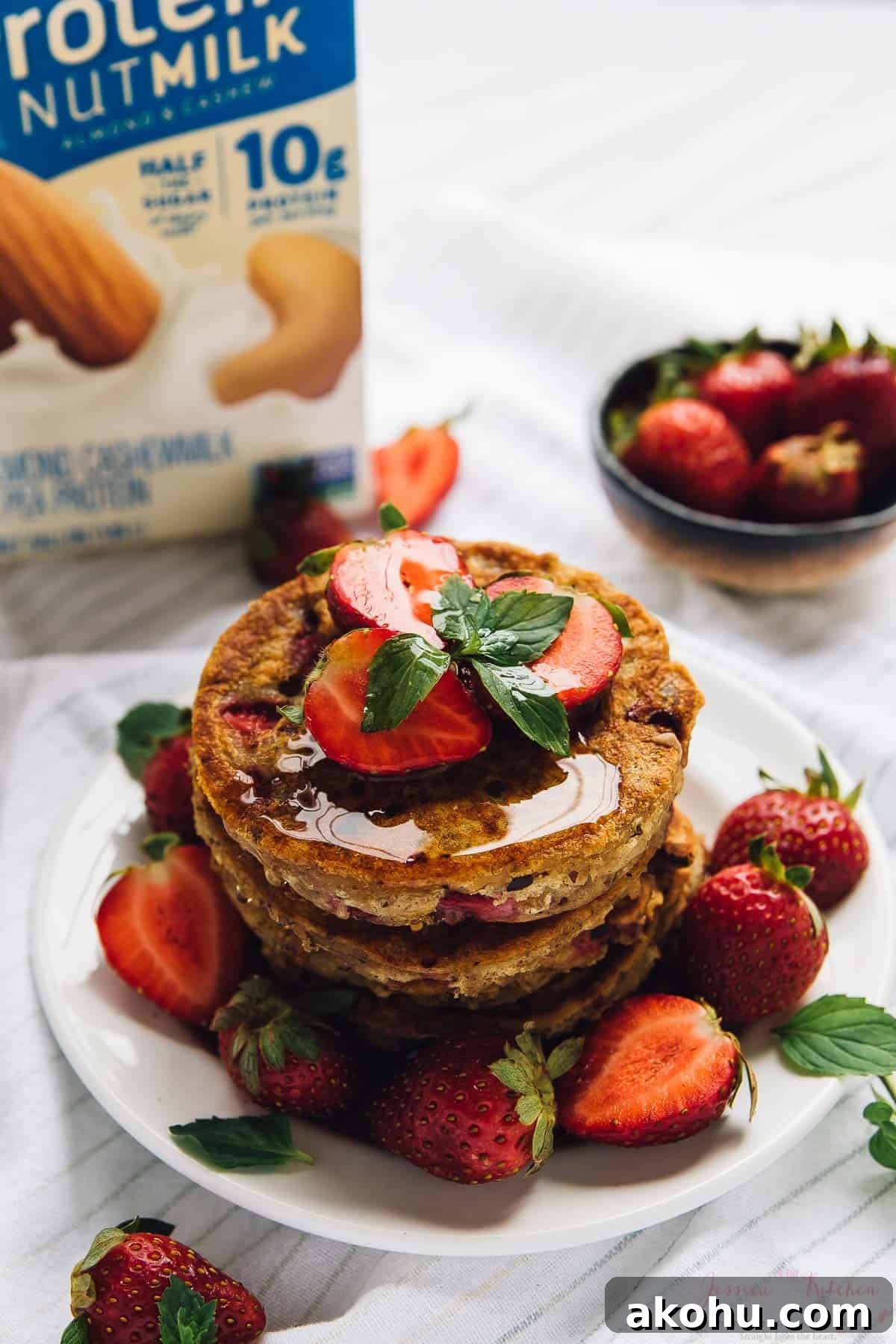 Strawberry pancakes—but make them gluten-free, plant-based, and PERFECTLY fluffy! Stack of strawberry pancakes on plate with fresh berries and syrup