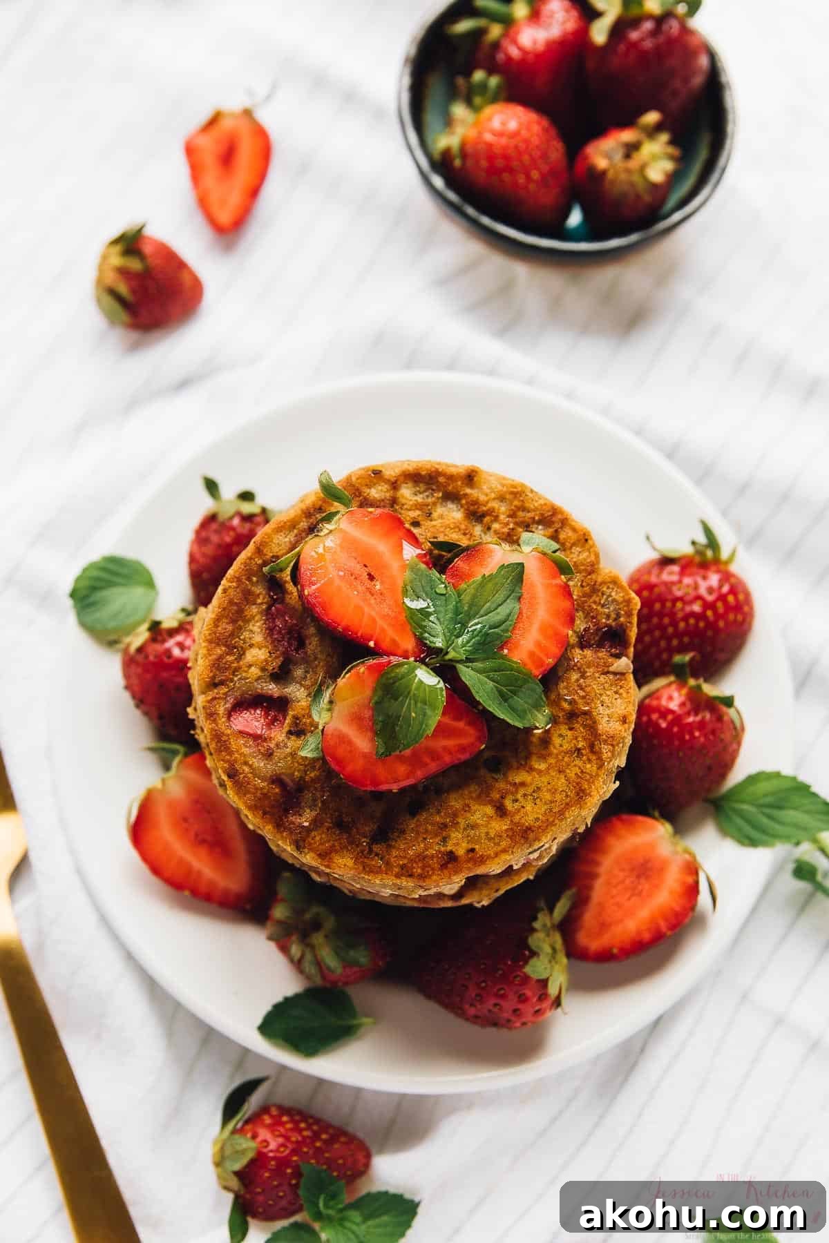 Strawberry pancakes—but make them gluten-free, plant-based, and PERFECTLY fluffy! Overhead view of gluten-free vegan strawberry pancakes on plate