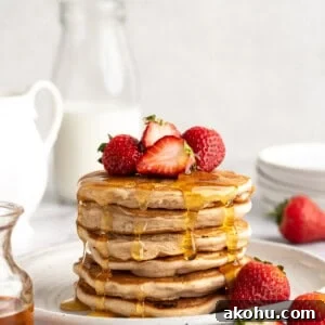 Gluten-Free Vegan Strawberry Pancakes Recipe for Fluffy Stacks 2 A stack of gluten-free strawberry pancakes topped with fresh strawberries and maple syrup.