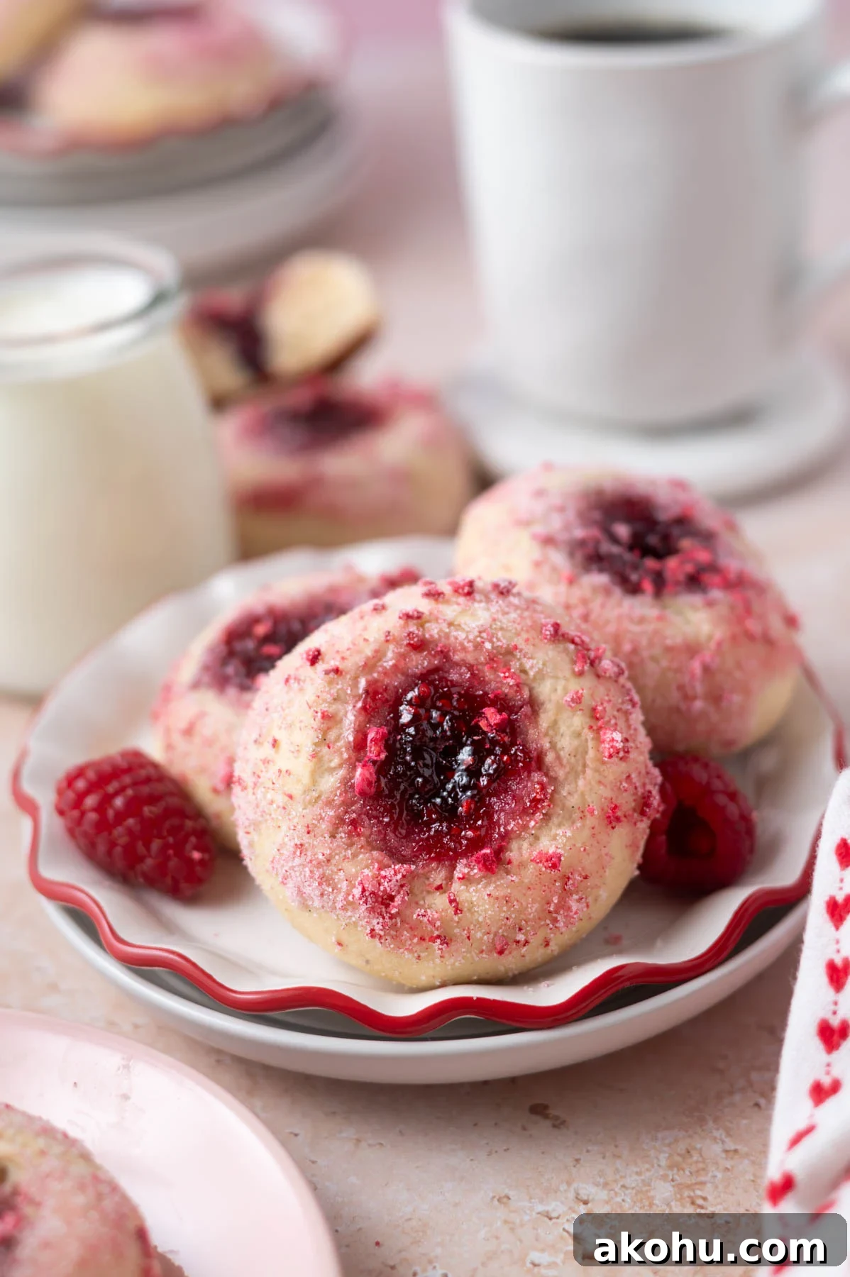 Yeast-Raised Baked Raspberry Donuts: Soft, Glazed Recipe 2 donuts with jam filled middles on a plate with a glass of milk and coffee in the background
