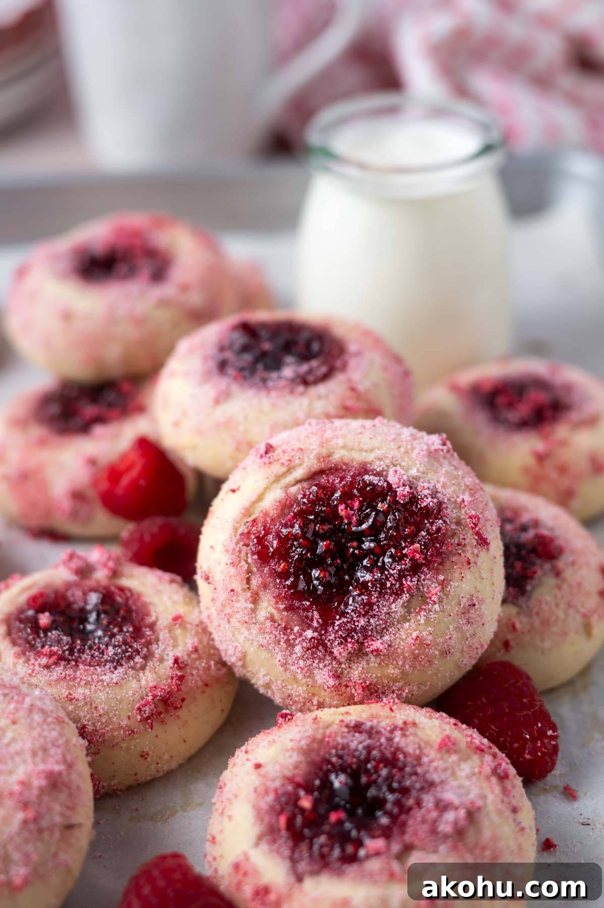 Yeast-Raised Baked Raspberry Donuts: Soft, Glazed Recipe 11 pile of raspberry donuts with fresh raspberries on parchment paper with a glass of milk and coffee
