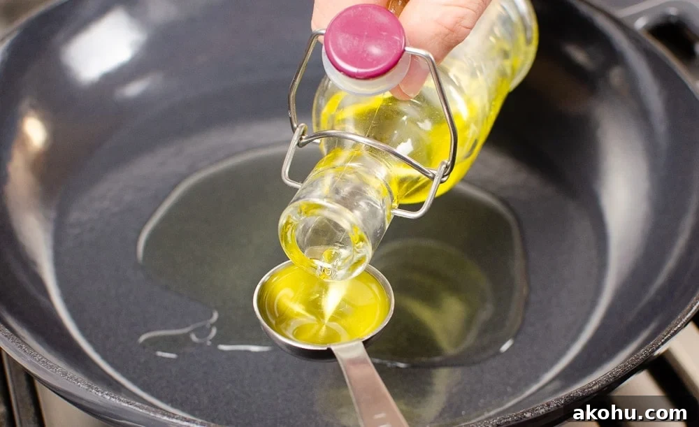 olive oil being poured into a pan to start cooing our sizzling spicy pork