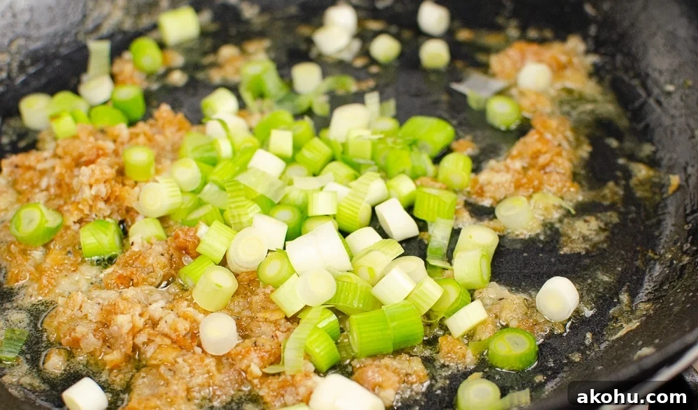 chopped spring onions in a pan cooking our sizzling spicy pork