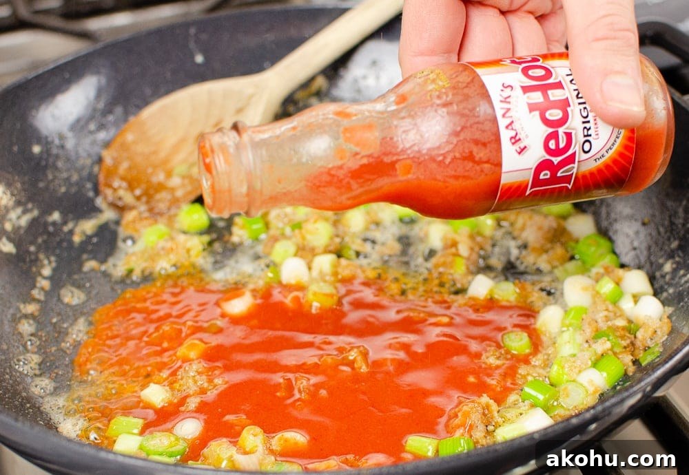 Franks hot sauce being added to the pan.