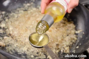 rice wine vinegar being poured into a cast iron pan to scrape of the bottom of the pan to cook our sizzling spicy pork