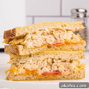 Air fryer tuna melt served on golden Texas toast with tomatoes and melted cheese cut in half and served on a round white plate,