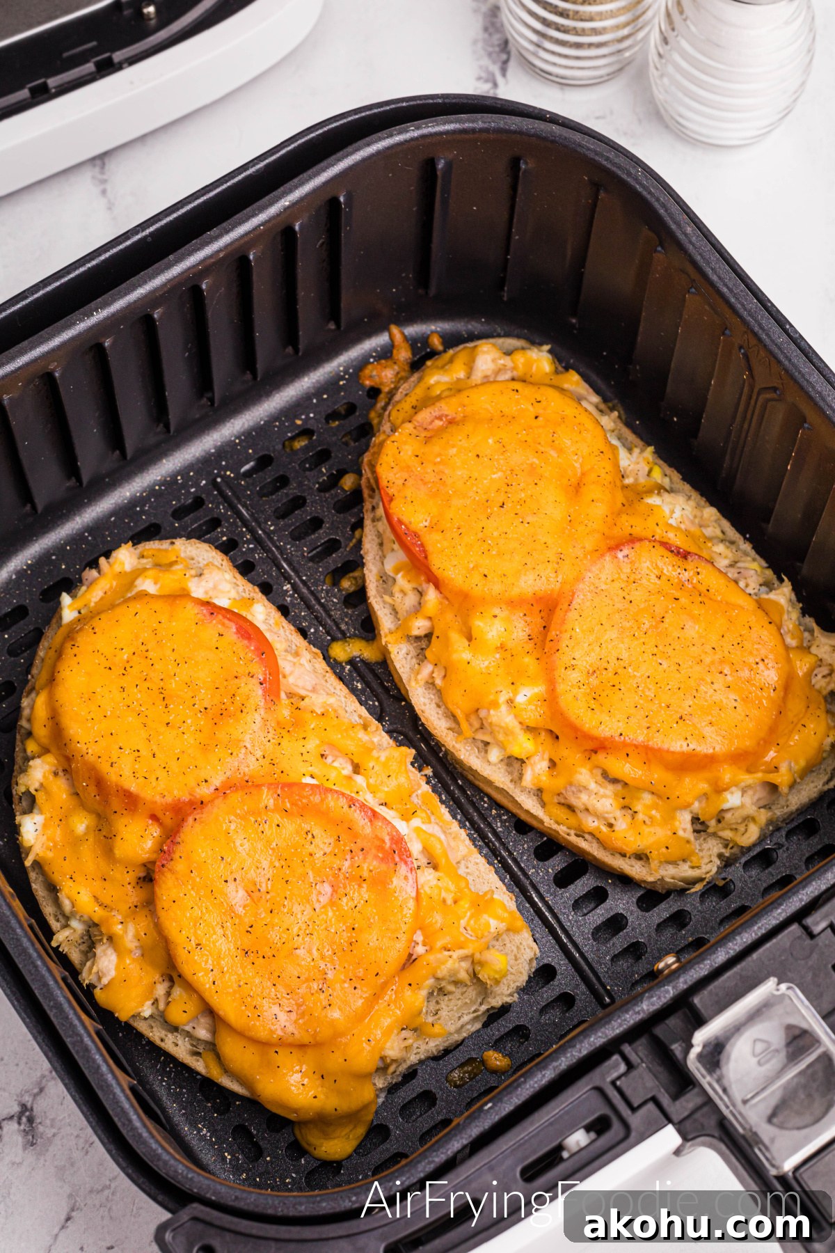Crispy Air Fryer Tuna Melt Sandwich Recipe 9 A close-up picture of a tuna melt in the air fryer basket with cheese melted on top.
