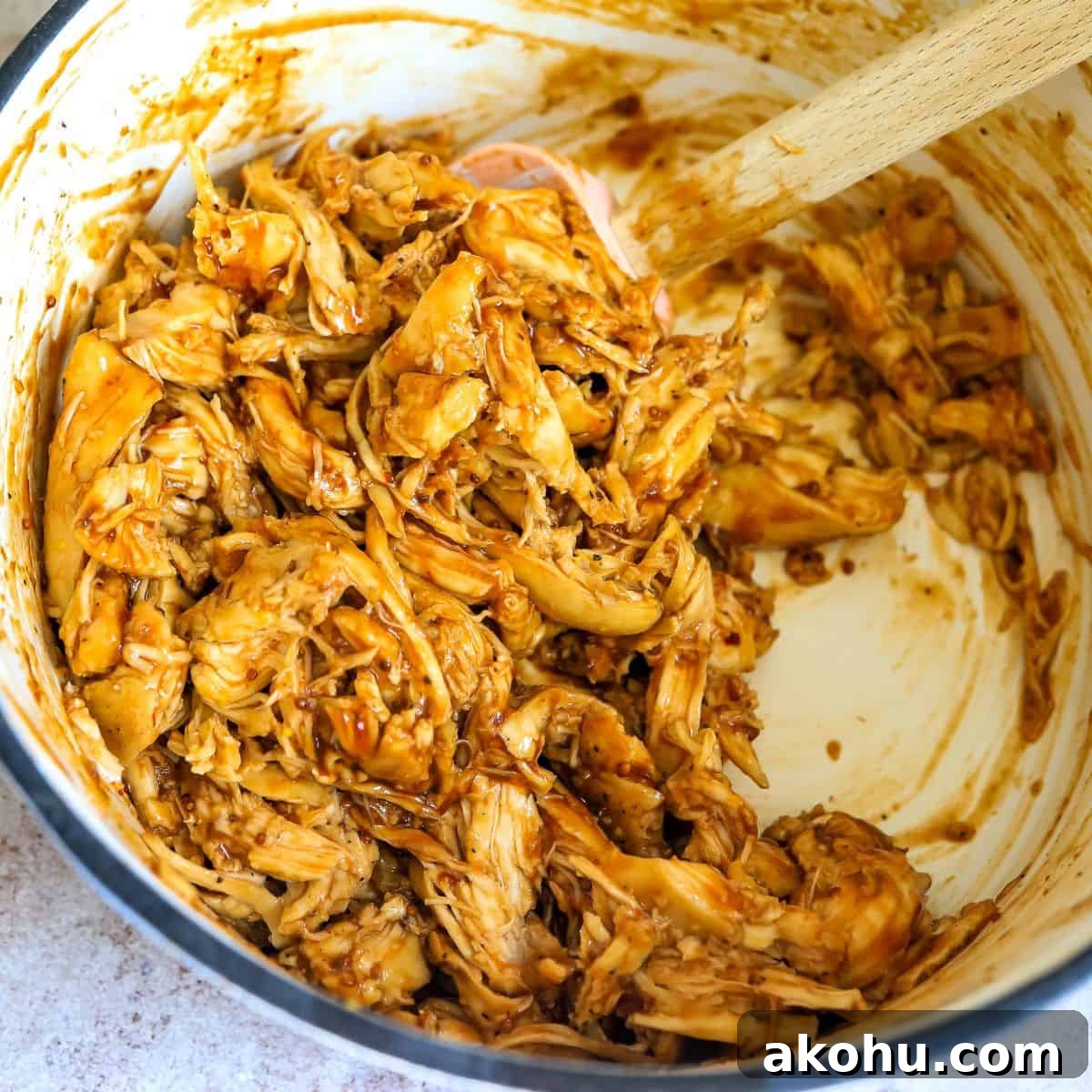 BBQ shredded chicken in a dutch oven with a spatula. 