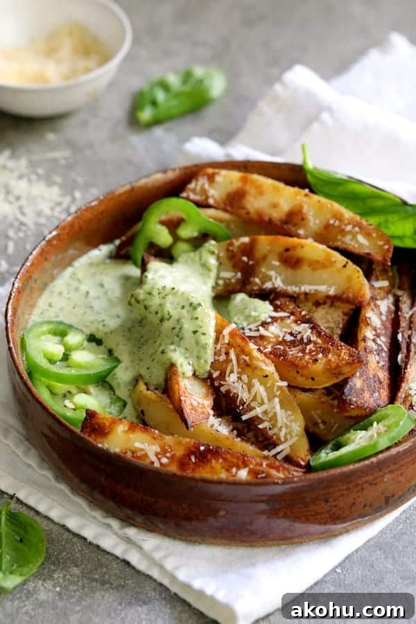 Photo of individual serving of fries with aioli garnished with jalapeno slices and fresh basil.