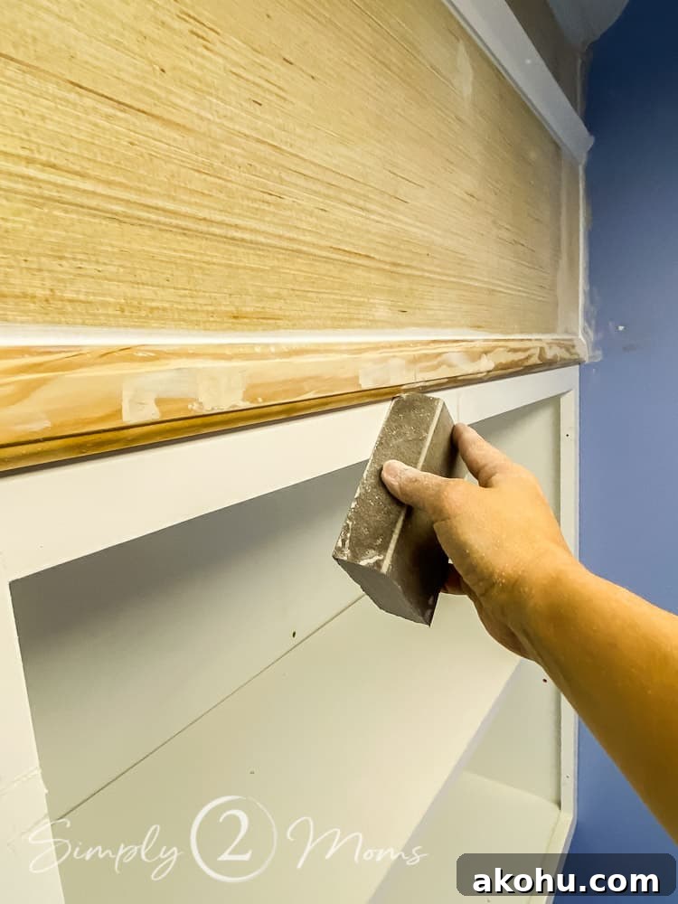 How to Close the Gap Above Kitchen Cabinets for a Finished Look 10 hand holding a sanding block and sanding wood putty on an above cabinet enclosure