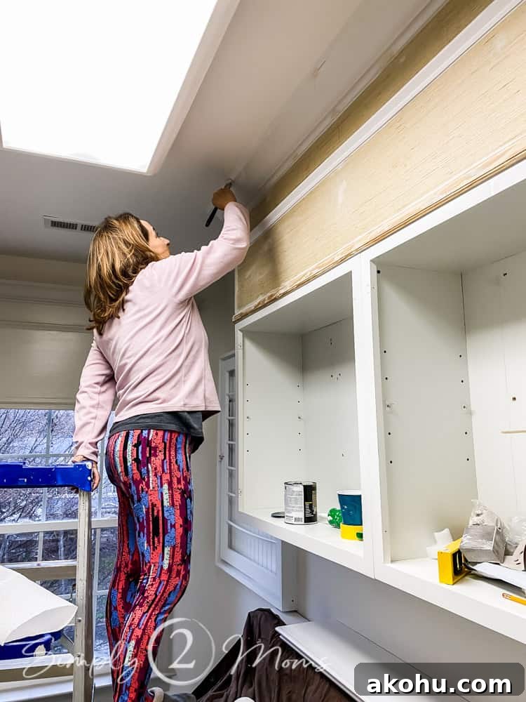 How to Close the Gap Above Kitchen Cabinets for a Finished Look 11 woman standing on washing machine painting cabinet soffit enclosure