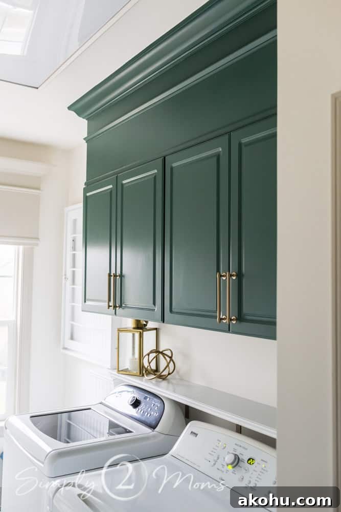How to Close the Gap Above Kitchen Cabinets for a Finished Look 14 Lafayette Green cabinets with gold handles and enclosed space above cabinets framed with crown molding in a laundry room over a washer and dryer