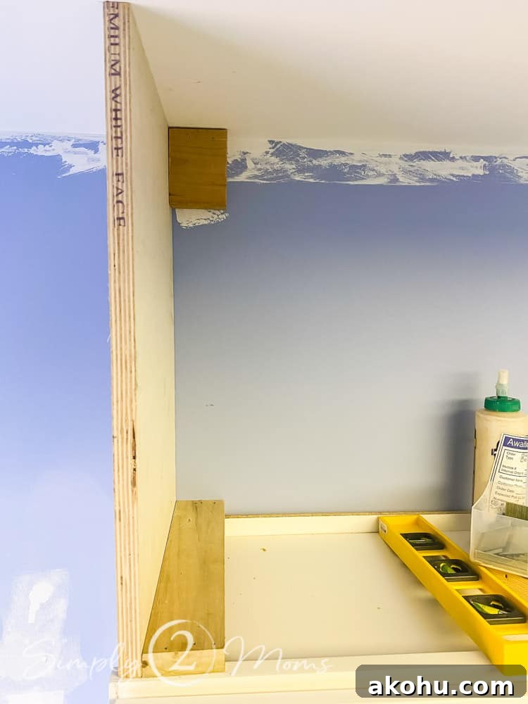 How to Close the Gap Above Kitchen Cabinets for a Finished Look 3 Vertical piece of wood attached to the edge on the top of a cabinet with wood block supports