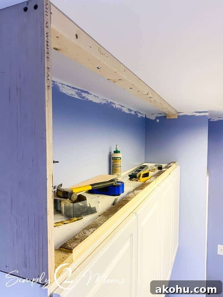 How to Close the Gap Above Kitchen Cabinets for a Finished Look 5 Rough wood box framing the open space above cabinets with assorted tools sitting on top of the cabinets