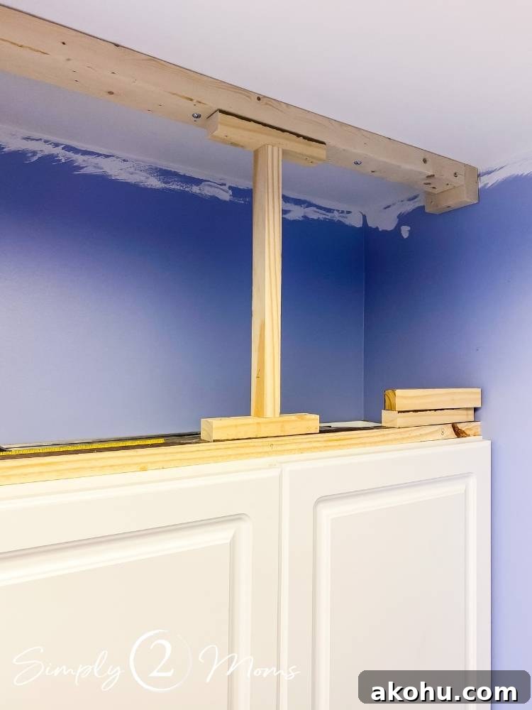 How to Close the Gap Above Kitchen Cabinets for a Finished Look 6 rough wood frame with supports above laundry room cabinets as a frame to attach wood and crown molding