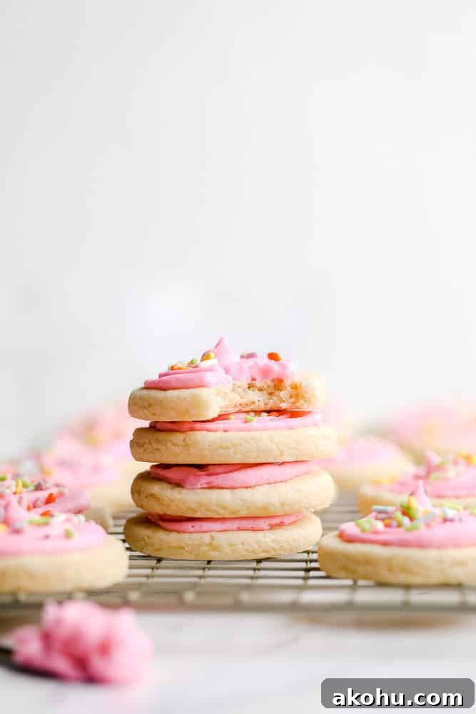 stack of 4 pink frosted cookies with sprinkles