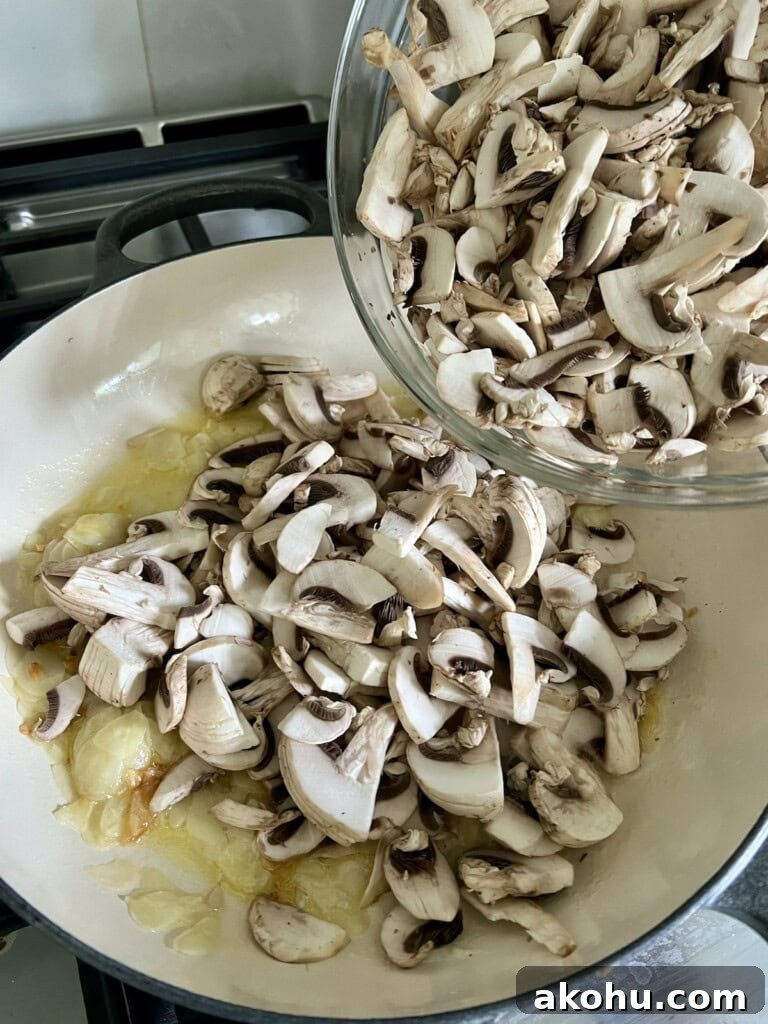 Adding chopped mushrooms to garlic in pan.