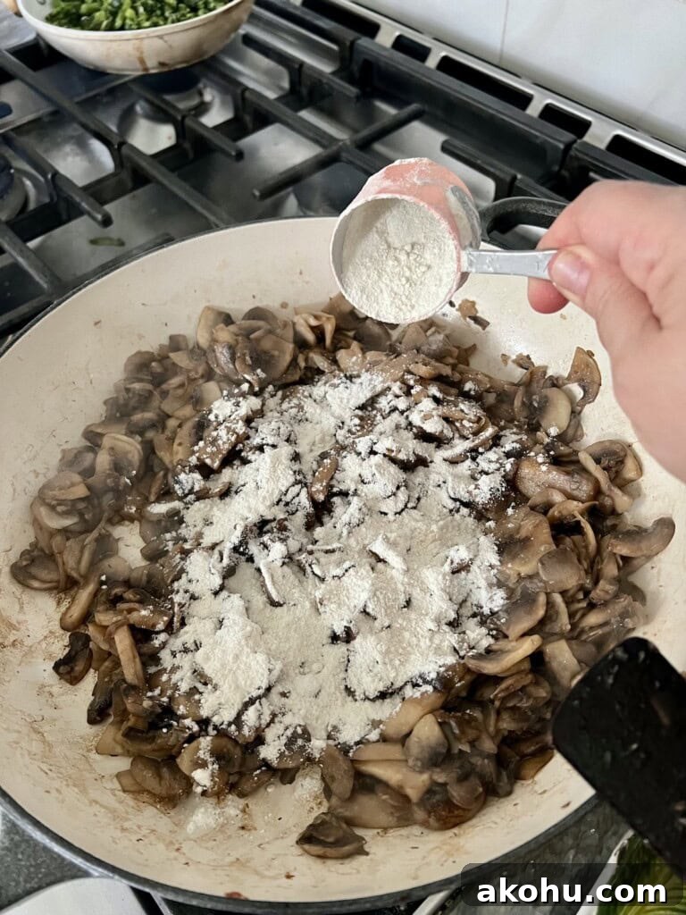 Sprinkling flour over cooked mushrooms.