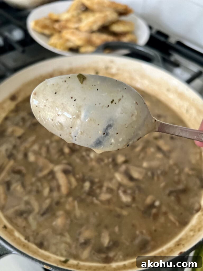 Checking the thickness of the chicken francese sauce with the back of a spoon.