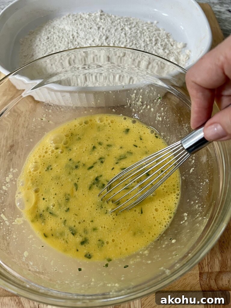 Whisking eggs, chopped parsley and grated cheese together, with flour in the backgound.