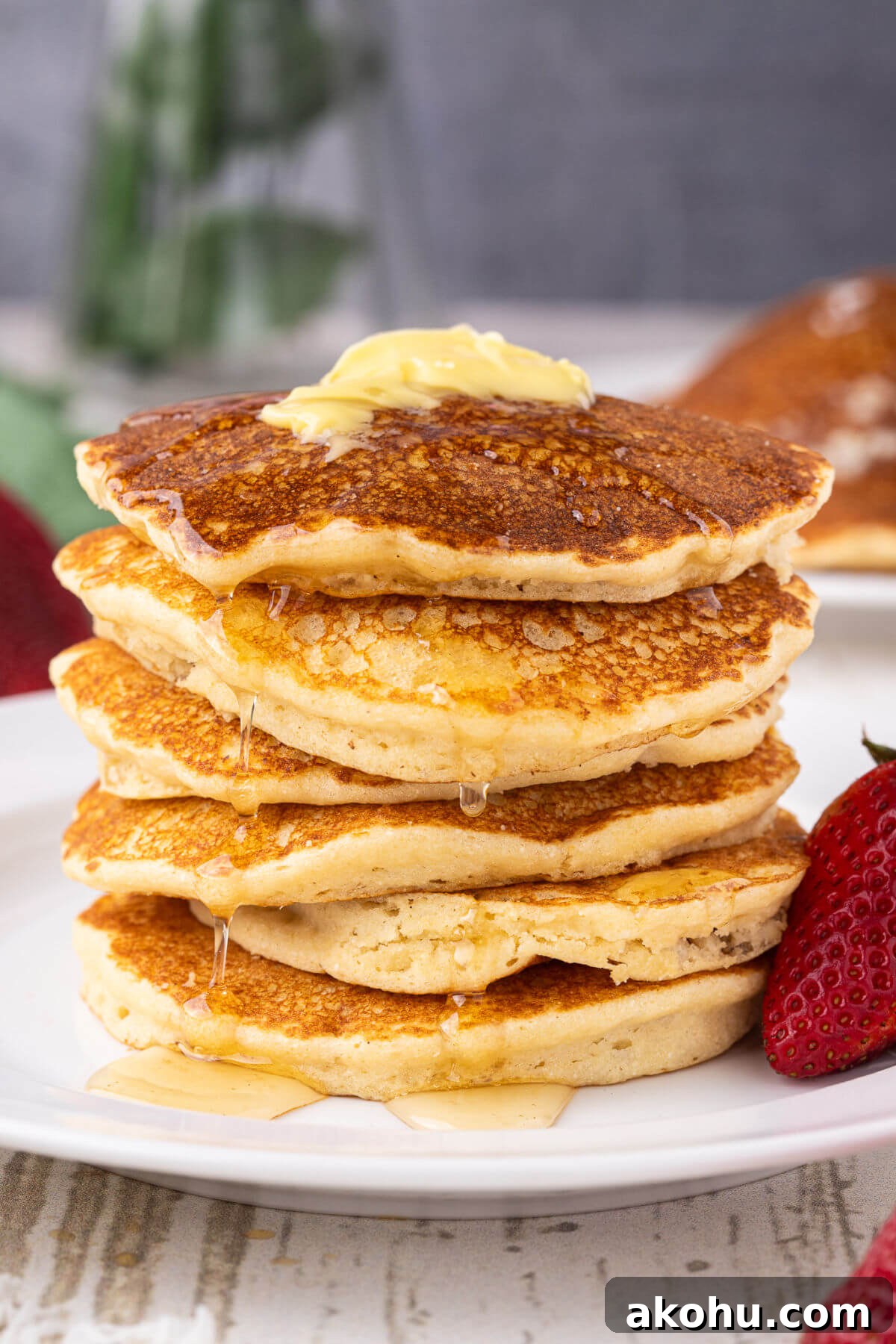 Stack of pancakes topped with butter and syrup.
