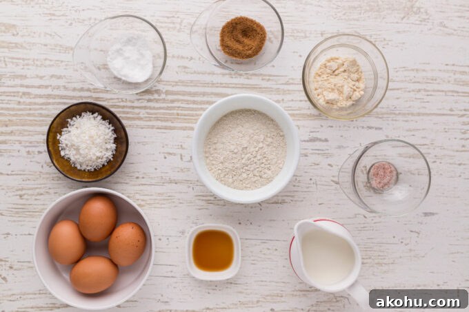 Flour, eggs, milk, and spices laid out in small bowls on a counter.