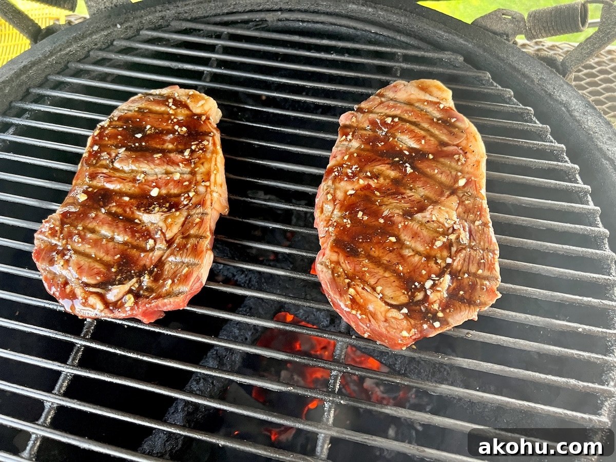 Grilled steaks with honey balsamic and garlic glaze. 2 ribeye steaks on a grill with glaze.