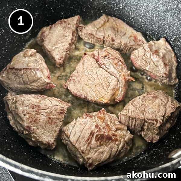 Beef being browned in a large pot with butter.