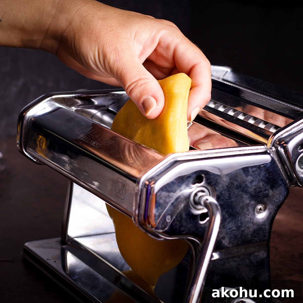 Feeding dough into a pasta machine on it's widest setting.