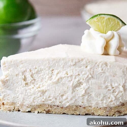 sideview of slice of keto no bake key lime cheesecake on a white serving dish topped with lime wedge and whipped cream